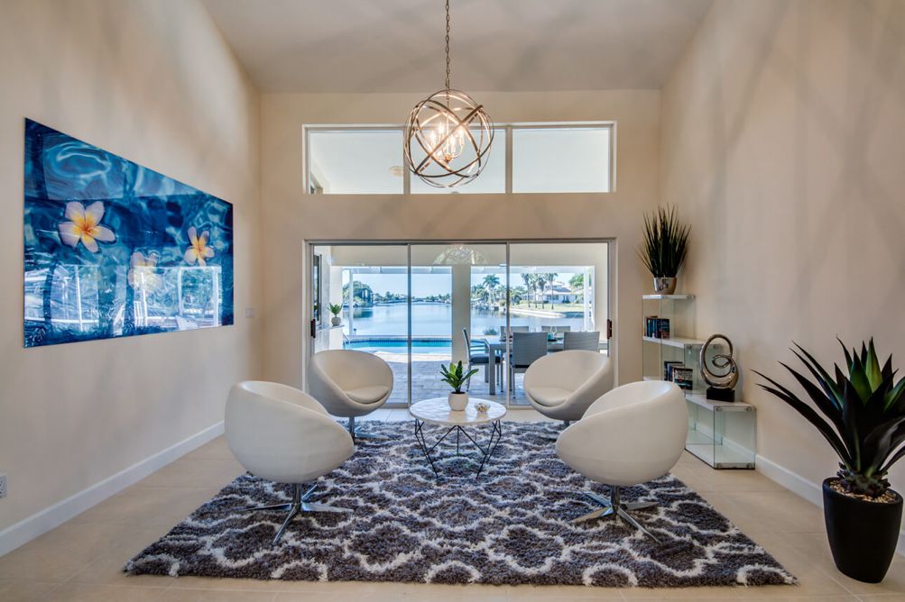 Formales Wohnzimmer mit weißen Drehsesseln und dunklem Teppich in der Villa Blue Pearl in Cape Coral, Florida