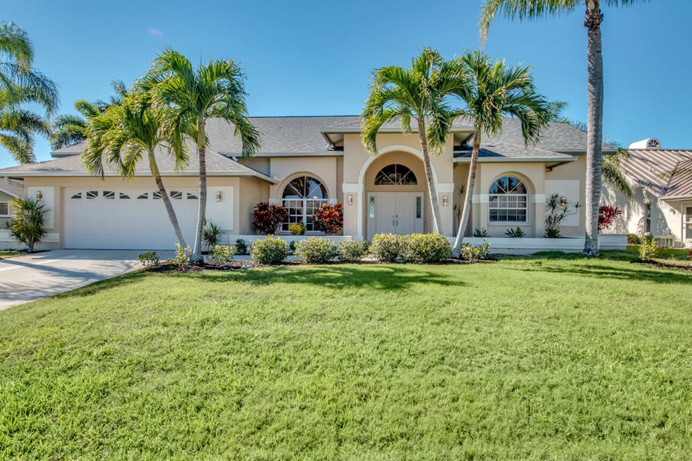 Vorderansicht und Vorgarten mit Palmen in der Villa Blue Pearl in Cape Coral, Florida