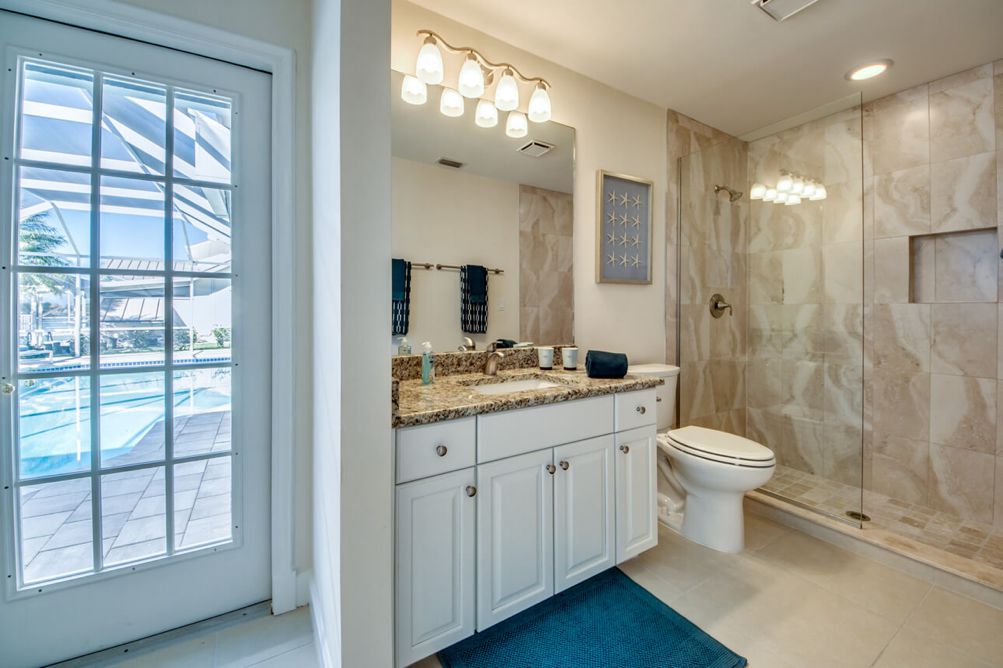 Gästebadezimmer mit begehbarer Dusche und Zugang zur Terrasse in der Villa Blue Pearl in Cape Coral, Florida