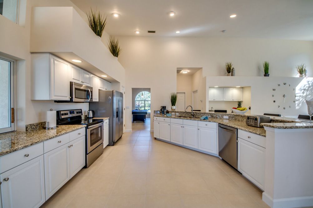 Großzügiger Küchenbereich und Mittelinsel mit weißen Fronten und silbernen Geräten in der Villa Blue Pearl in Cape Coral, Florida