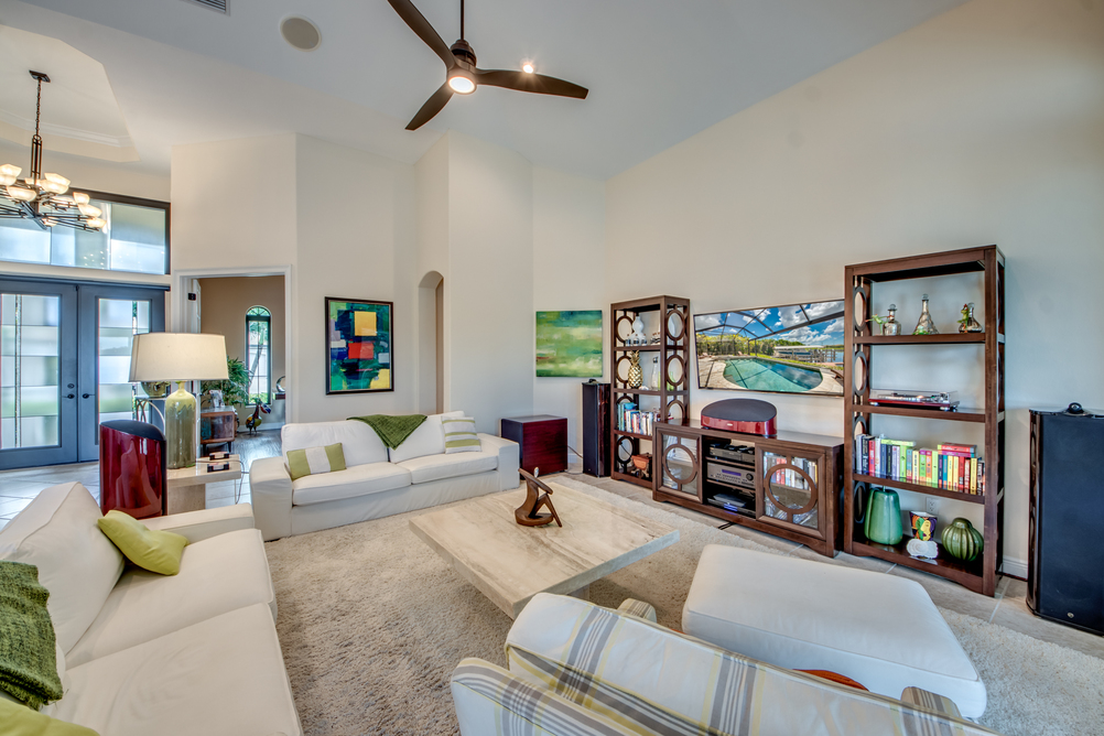 Wohnbereich mit hellen Sofas und dunklen Holzregalen in der Villa Regency in Cape Coral, Florida