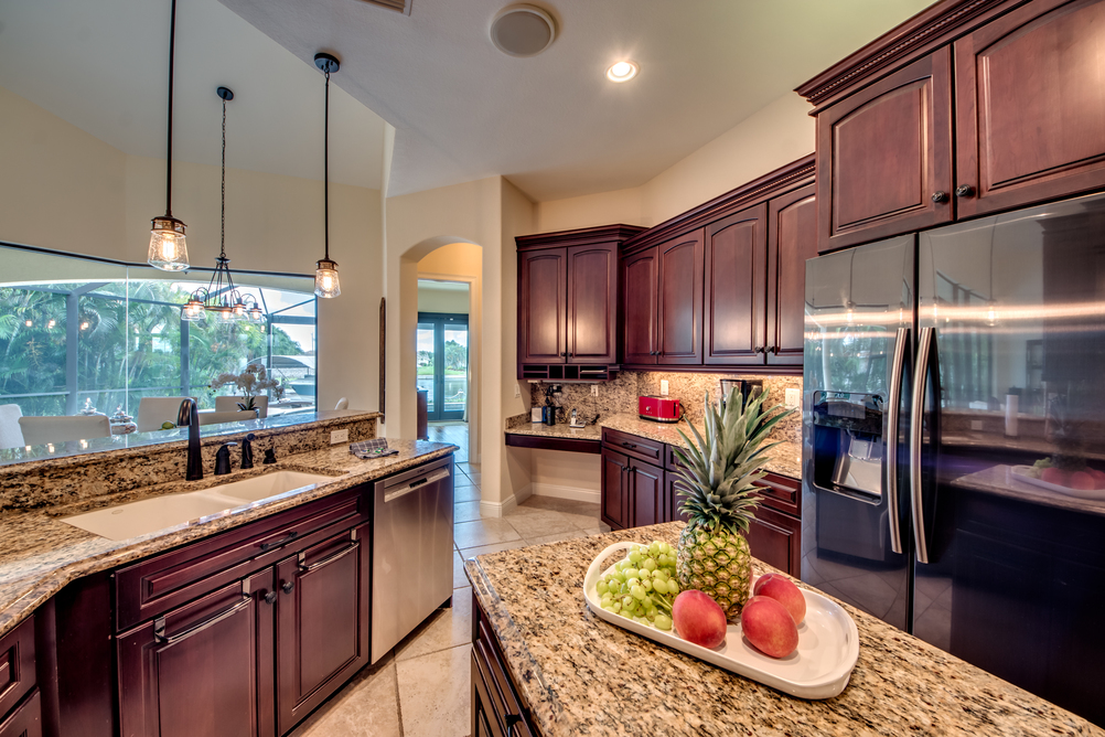 Küche mit dunklen Holzfronten und Arbeitsplatten in Marmoroptik in der Villa Regency in Cape Coral, Florida