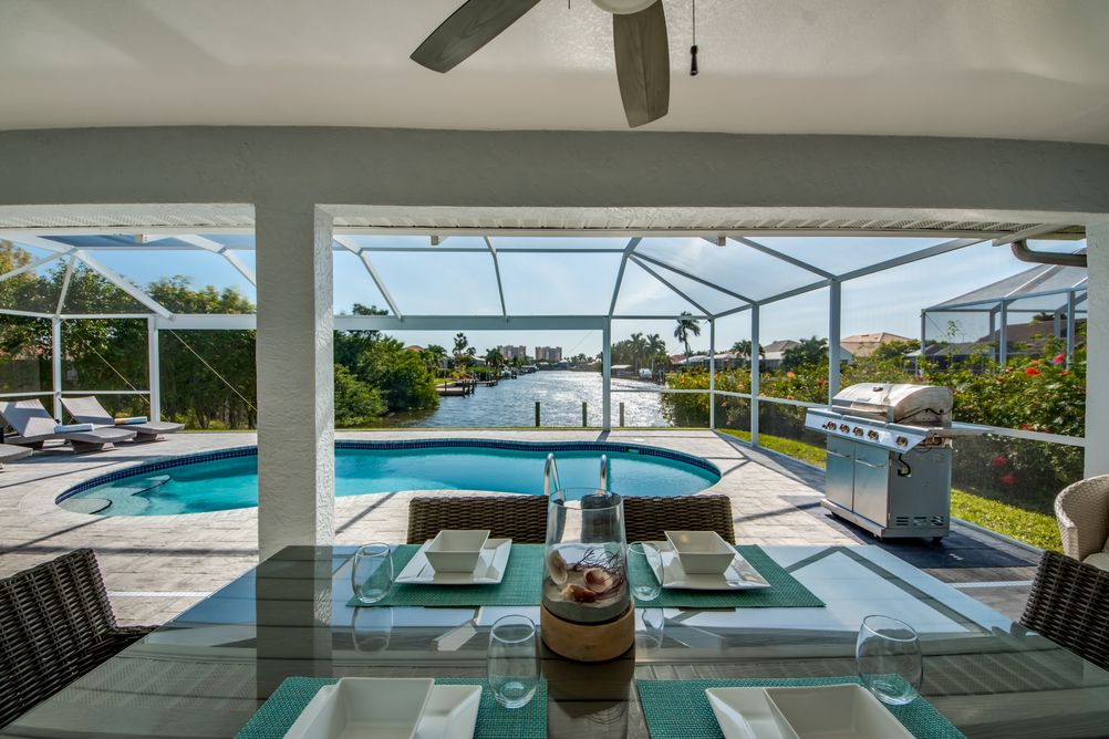 Esstisch der Villa Sunshine Bay mit dem Ausblick auf den Grill, Pool und den Kanal